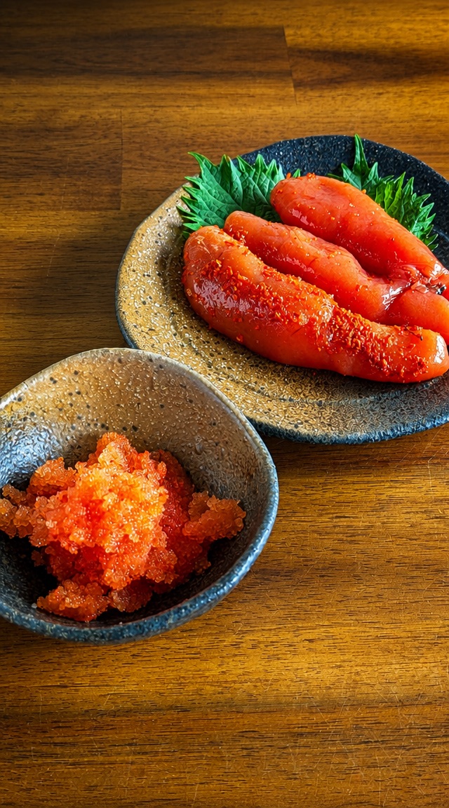 器に盛った明太子と、皿に並べた一腹の辛子明太子 — 表面に唐辛子がまぶされ、たらこより赤みが強い